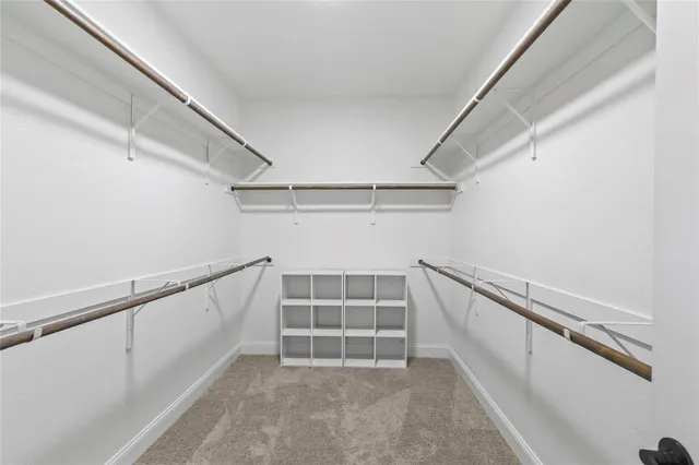 a view of an empty room with a window and a kitchen