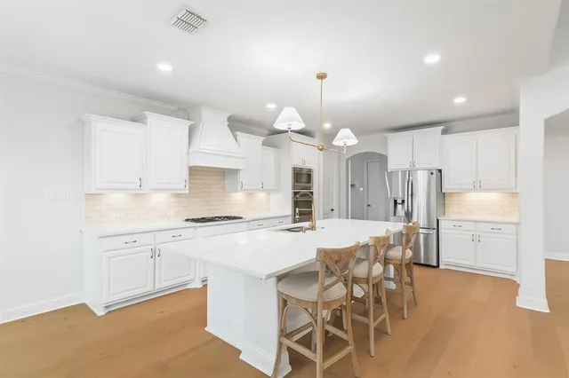 a kitchen with a refrigerator a sink dishwasher a stove a dining table and chairs with wooden floor