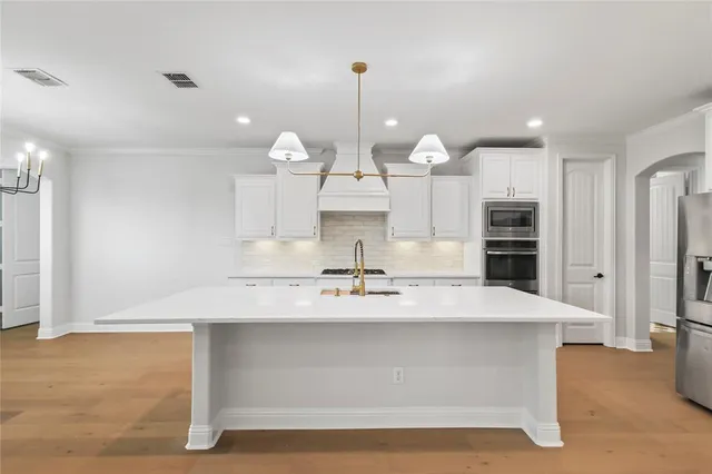 a view of a kitchen with kitchen island a sink and wooden floor