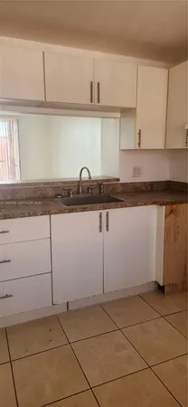a kitchen with granite countertop a sink a stove and cabinets