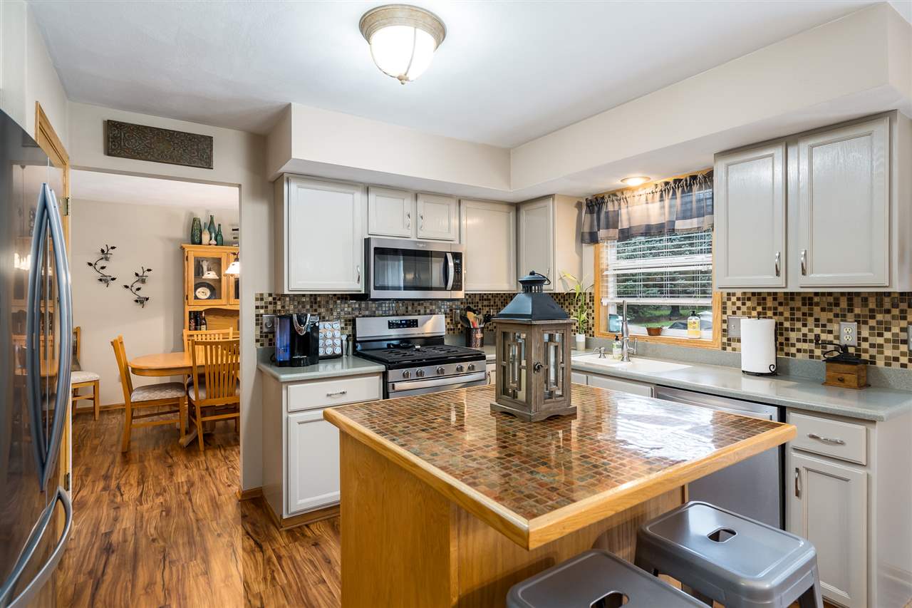 9414 Rambouillet Ridge Roscoe, IL 61073 - Photo 22 of 39 a kitchen with a stove a sink a microwave a dining table and chairs