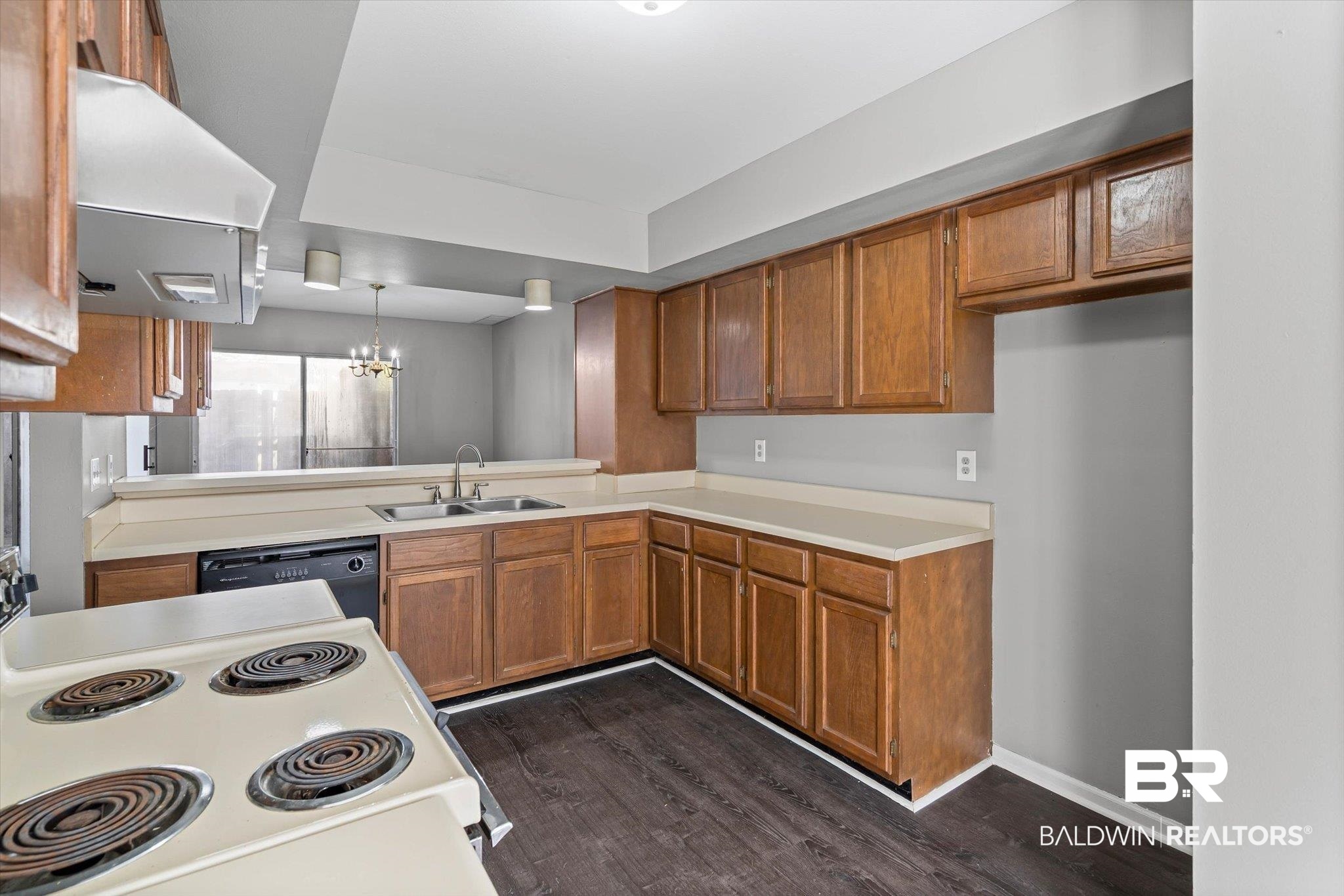 6701 Dickens Ferry Road, Unit 100 Mobile, AL 36608 - Photo 2 of 24 Kitchen with brown cabinets, a chandelier, electric stove, exhaust hood, and dark wood-type flooring