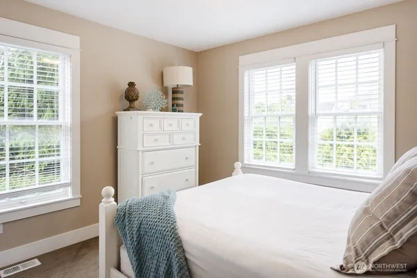 a bedroom with a bed and a dresser next to a window