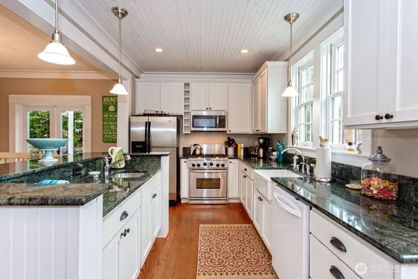 a kitchen with granite countertop a sink stainless steel appliances and cabinets