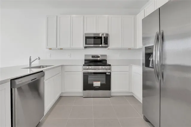 a kitchen with white cabinets and stainless steel appliances