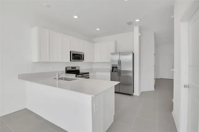 a kitchen with stainless steel appliances granite countertop a refrigerator a stove a sink a microwave a refrigerator and white cabinets with wooden floor