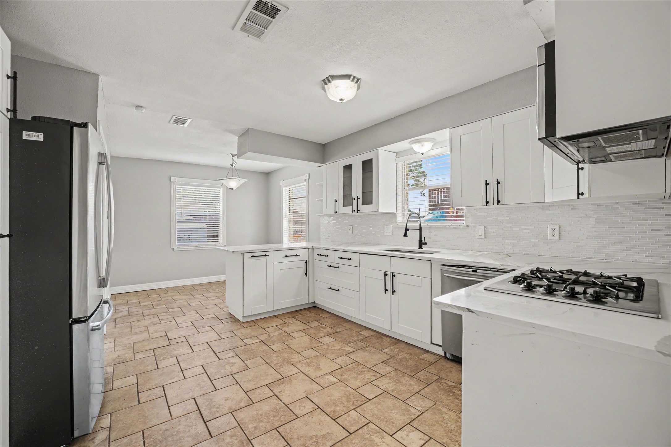 8330 Springtime Lane Houston, TX 77075 - Photo 4 of 27 Bright and spacious kitchen featuring modern white cabinetry, sleek stainless steel appliances, and a convenient gas cooktop.