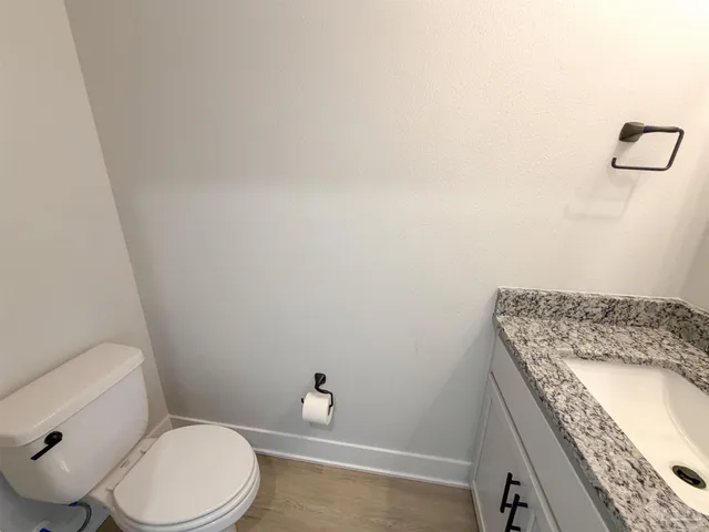 a bathroom with a granite countertop toilet and a sink