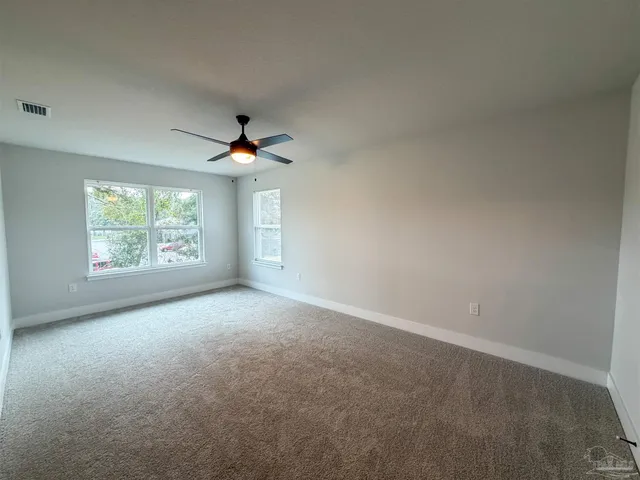 en empty room with windows and ceiling fan