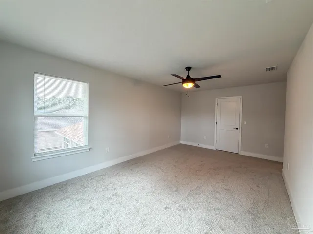 an empty room with windows and ceiling fan