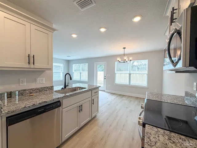 a kitchen with stainless steel appliances granite countertop a sink stove and cabinets