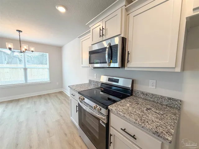 a kitchen with stainless steel appliances granite countertop a stove a microwave and a white cabinets