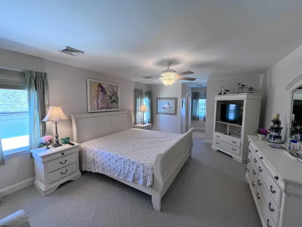 a spacious bedroom with a bed a window and dresser