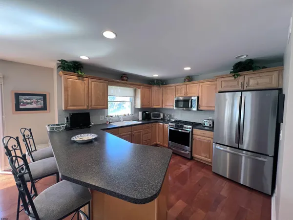 a kitchen with stainless steel appliances granite countertop a refrigerator a stove a sink dishwasher a dining table and chairs with wooden floor