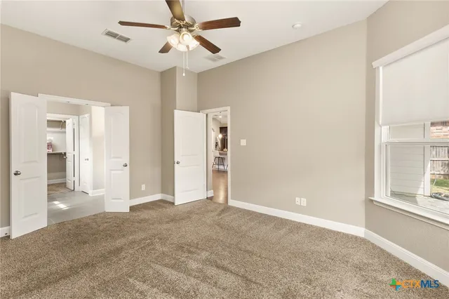 a view of a big room with windows and ceiling fan