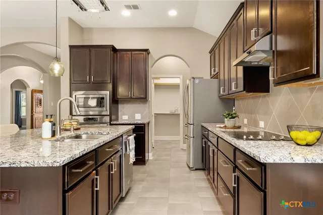 a kitchen with stainless steel appliances granite countertop a sink a stove and cabinets