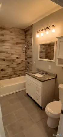 a bathroom with a granite countertop sink a toilet and bathtub