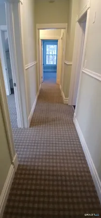 a view of an empty room with wooden floor and a bathroom