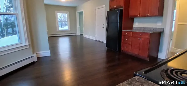 a kitchen with granite countertop wooden cabinets and a refrigerator