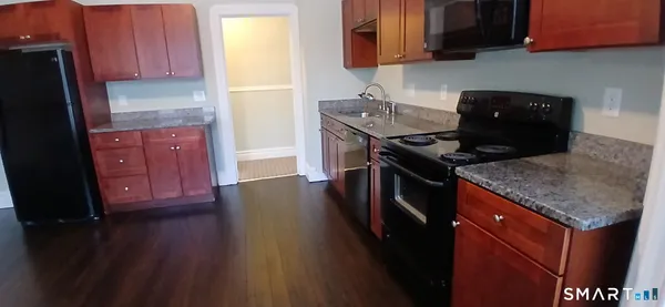 a kitchen with stainless steel appliances granite countertop a stove a refrigerator a sink dishwasher and wooden cabinets with wooden floor