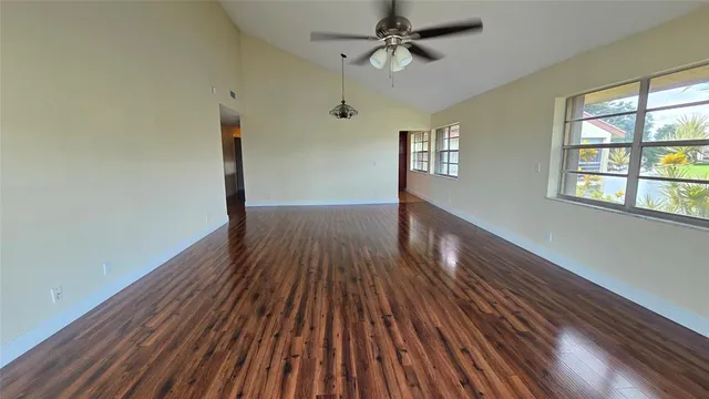 a view of empty room with wooden floor and fan