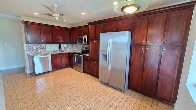 a kitchen with stainless steel appliances granite countertop a refrigerator a sink and wooden cabinets
