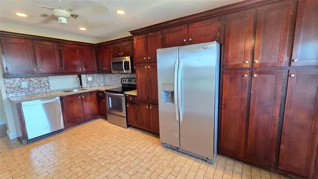 a kitchen with granite countertop stainless steel appliances a refrigerator and cabinets