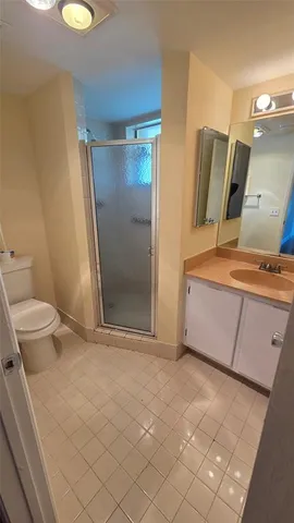 a bathroom with a granite countertop sink a toilet a mirror and shower