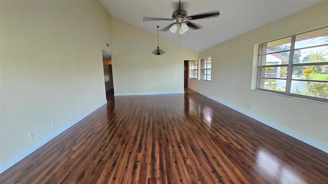 a view of empty room with wooden floor and fan