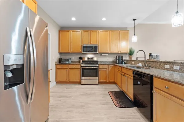 a kitchen with granite countertop a refrigerator sink and cabinets