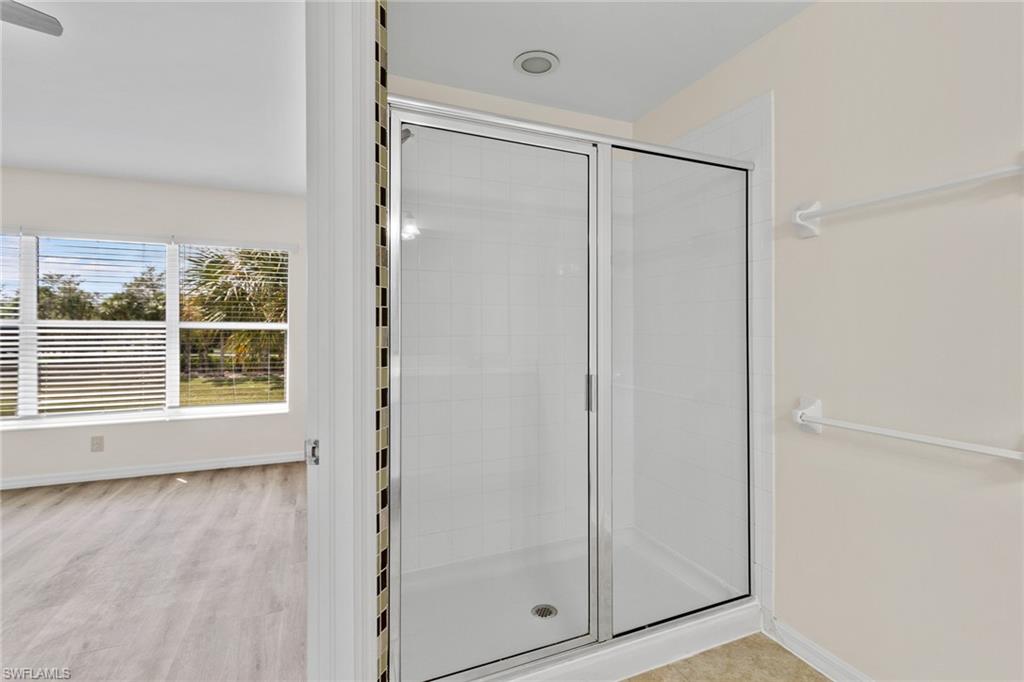 16235 Ravina Way Naples, FL 34110 - Photo 12 of 18 Glass-enclosed shower with tile surround, recessed lighting, and adjacent closet shelving