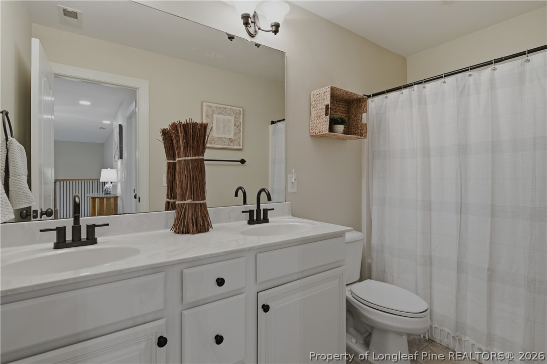 14 Spring Water Court Spring Lake, NC 28390 - Photo 17 of 34 a bathroom with a double vanity sink toilet and mirror