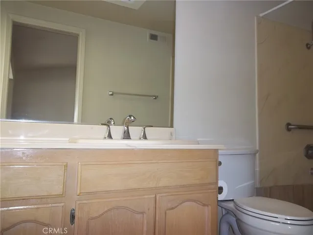 a bathroom with a granite countertop toilet sink mirror and vanity