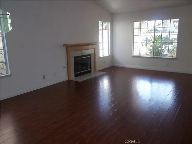 an empty room with wooden floor fireplace and windows
