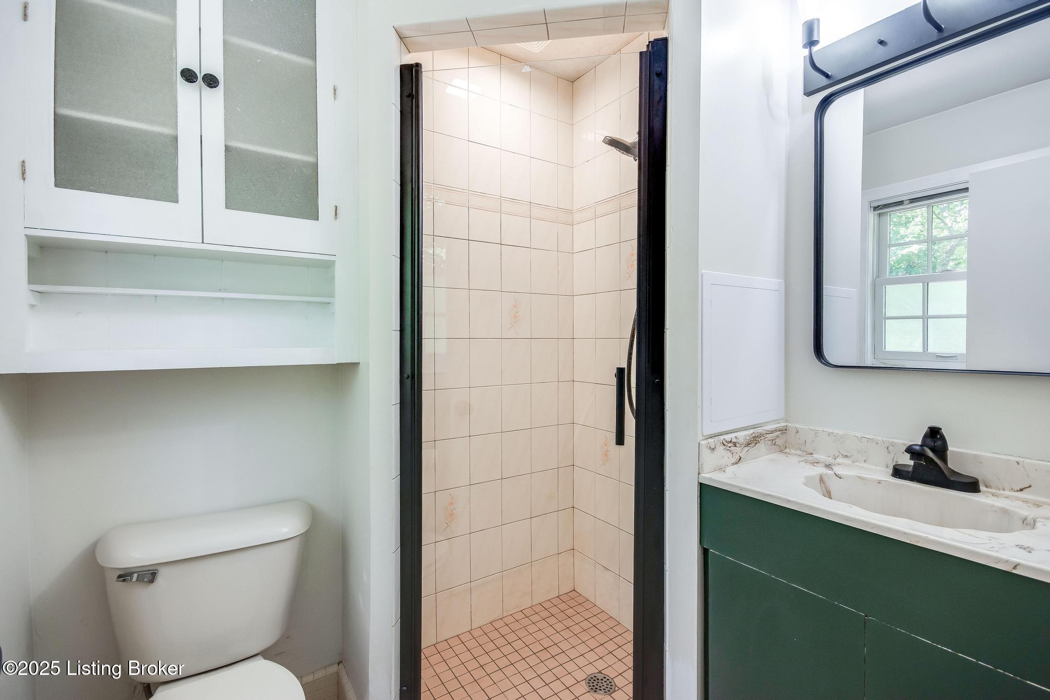 9611 Fairground Road Louisville, KY 40291 - Photo 24 of 57 Primary Bathroom with tile flooring, new toilet, new shower door, new light fixture, tiled walk-in shower, new faucet and half smoke glass window.