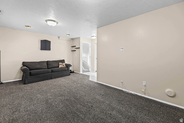 5896 South 3950th Street West Roy, UT 84067 - Photo 16 of 29 Living area featuring a textured ceiling and light colored carpet