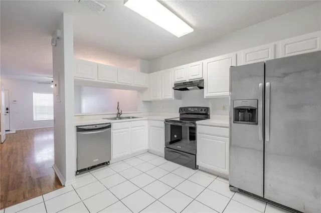 a kitchen with granite countertop white cabinets and stainless steel appliances