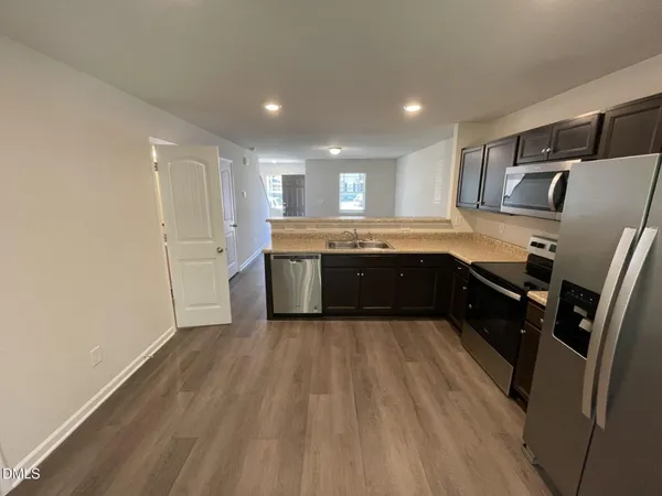 a large kitchen with wooden floors and stainless steel appliances