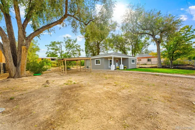 front view of house with a yard and trees