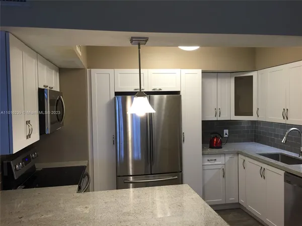 a kitchen with stainless steel appliances granite countertop a refrigerator and a sink