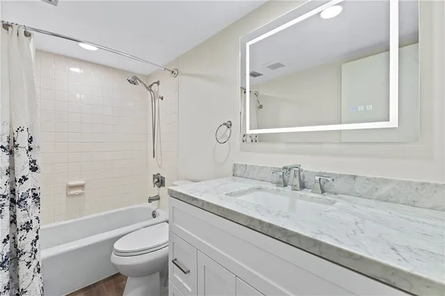 a bathroom with a granite countertop sink toilet mirror and shower