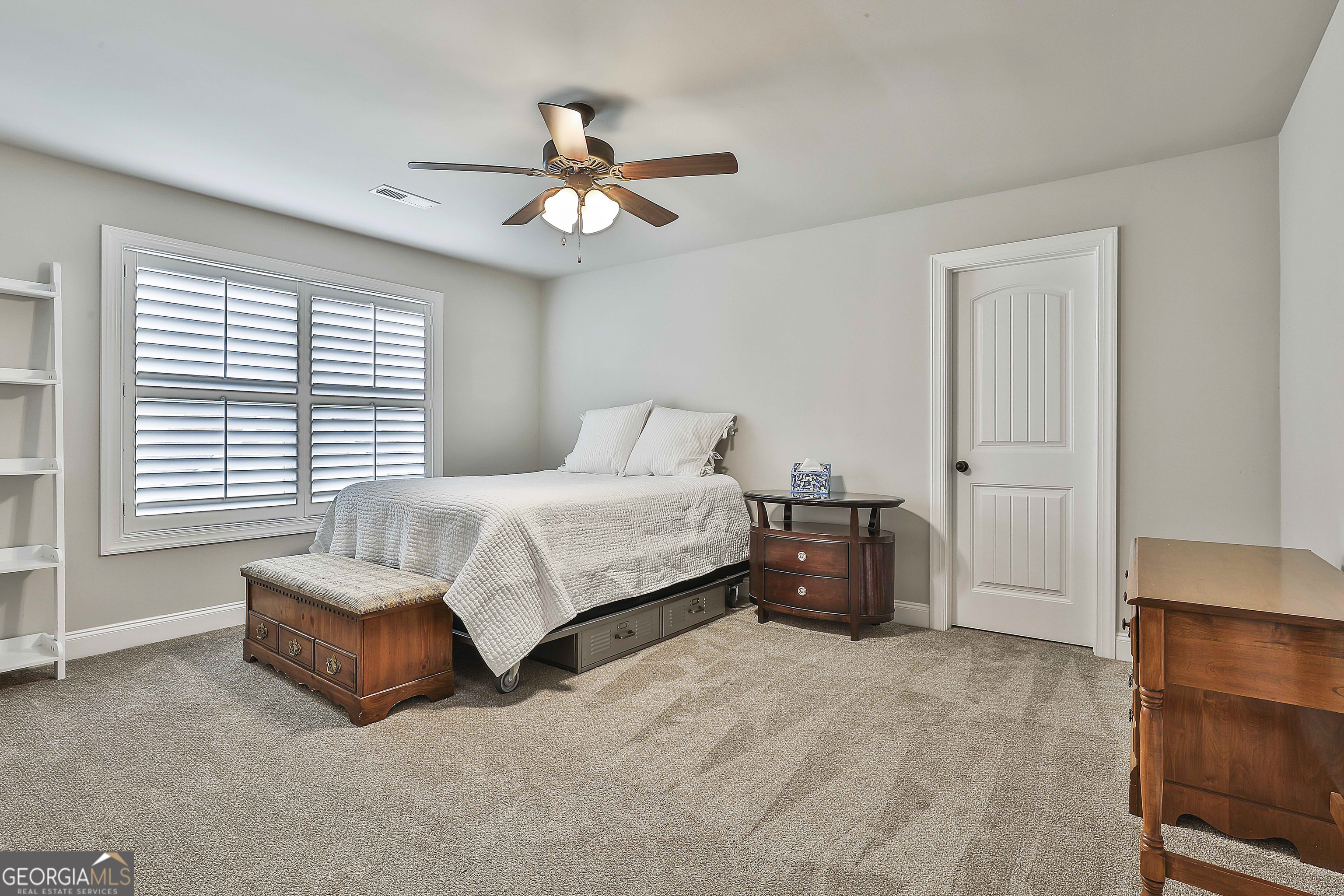 155 Wet Stone Road Senoia, GA 30276 - Photo 37 of 46 a spacious bedroom with a bed and a chandelier