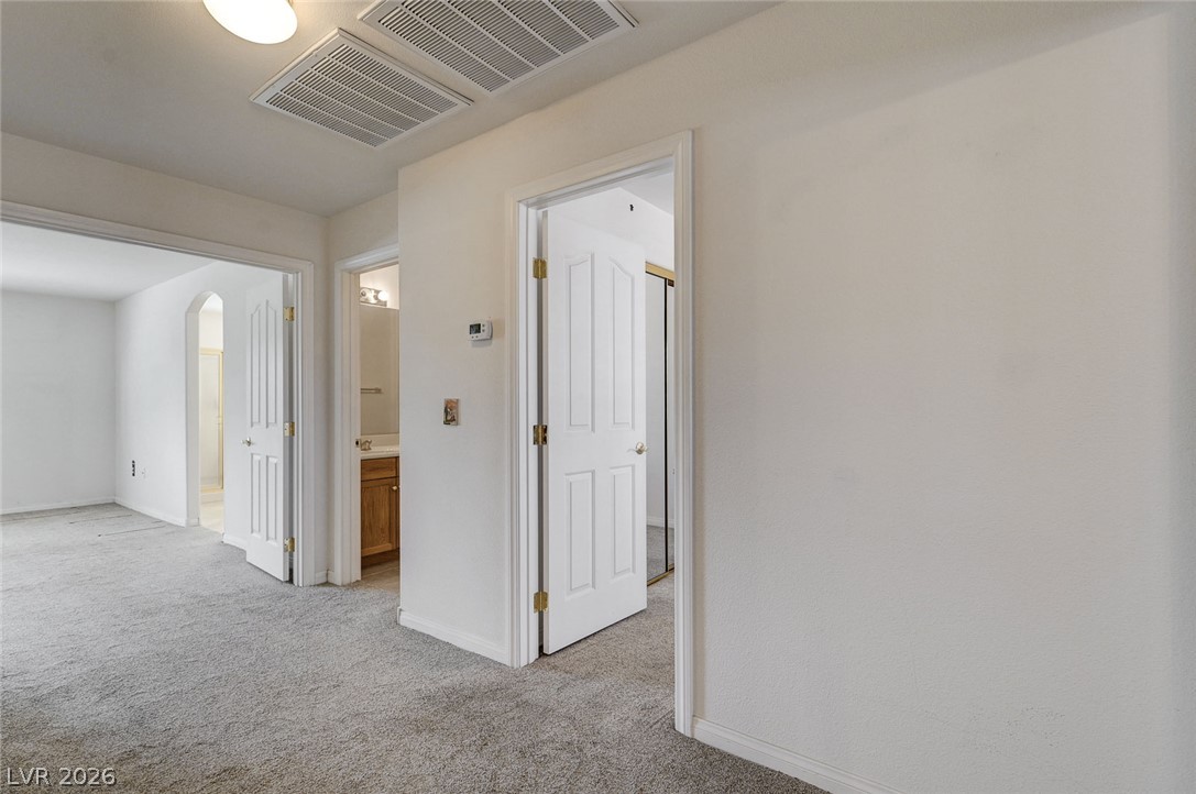 1479 Orange Jubilee Road Henderson, NV 89014 - Photo 15 of 36 A well-lit, neutral-toned interior hallway connects several rooms, offering a glimpse into adjoining spaces.