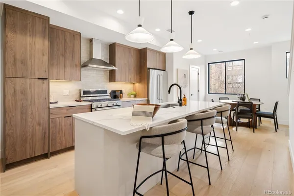 a kitchen with stainless steel appliances kitchen island a table chairs in it and wooden floors