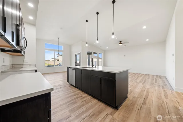 a large kitchen with a large counter top a sink stainless steel appliances and cabinets