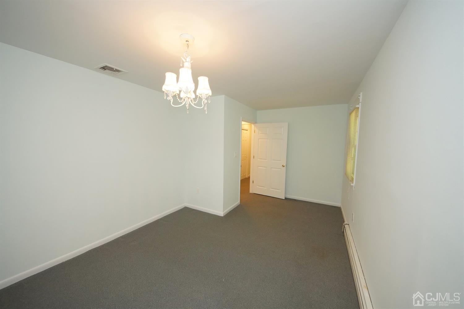 238 New Road Monmouth Junction, NJ 08852 - Photo 30 of 63 en empty room with wooden floor and chandelier