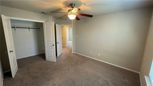 an empty room with closet and a chandelier fan
