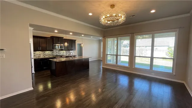 a living room with stainless steel appliances kitchen island granite countertop furniture a large window and wooden floor