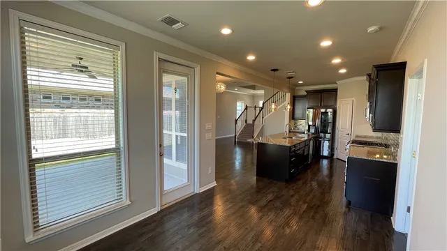 a view of a living room with stainless steel appliances wooden floor and a large window