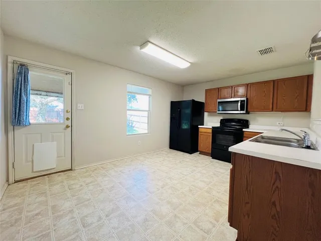 a kitchen with granite countertop a refrigerator and a stove top oven